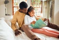 Black family, reading book and learning while on a bed for story time in house bedroom. Man or dad teaching girl child Royalty Free Stock Photo