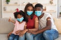 Black Family Of Three Wearing Medical Masks Posing At Home After Vaccination