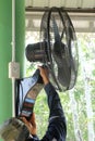 A black fan is being installed under the roof of the building to reduce heat and ventilate.