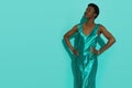 Black fashion model in a turquoise satin dress is posing with hands on hip Royalty Free Stock Photo