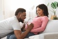 Black father holding headset on pregnant woman belly Royalty Free Stock Photo