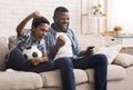 Black father and son soccer fans watching football on tv Royalty Free Stock Photo