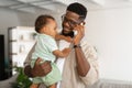 Black father talking on phone and holding baby on hands Royalty Free Stock Photo