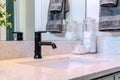 Black faucet and single ceramic sink on the clean bathroom vanity of a home