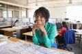 Black female architect leans on desk smiling in busy office Royalty Free Stock Photo