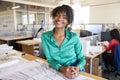 Black female architect leans on desk smiling in busy office Royalty Free Stock Photo