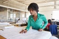 Black female architect studying plans in open plan office Royalty Free Stock Photo