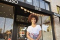 Black female business owner standing outside cafe shopfront