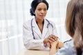 Black female doctor holding hands young woman patient with love, care, helping, encourage and empathy at hospital