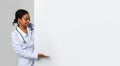 Black female doctor looking and pointing at big blank advertising board Royalty Free Stock Photo