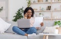 Black female entrepreneur working from home, discussing documents with client on cellphone