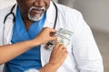 Black female hand putting money in doctor's pocket, closeup Royalty Free Stock Photo