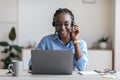 Black female manager wearing headset and using laptop in office, consulting client Royalty Free Stock Photo
