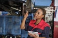 Black female mechanic checks car\'s brake disc and repairs checklist at garage.