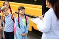 Black female teacher updating check list of children entering school bus Royalty Free Stock Photo