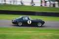 Black Ferrari 250 GT SWB is driving along a road during the Goodwood Revival festival