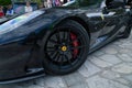 A black Ferrari is parked on a cobblestone driveway