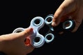 Black fidget spinner held in small boy hand and white fidget spinner in small girls hand, black background