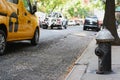 Black fire hydrant on city sidewalk, traffic passing Royalty Free Stock Photo