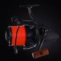 Black fishing reel with orange fishing line, on a black background. Close-up Royalty Free Stock Photo