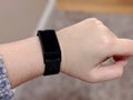 Black fitness tracker with metal band on a wrist, held up in front of a person