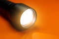 Black Flashlight and a ray of light on the orange background. Close up photo Royalty Free Stock Photo