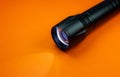 Black Flashlight and a ray of light on the orange background. Close up photo Royalty Free Stock Photo