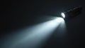 Black flashlight shines bright beam of light on dark background. Portable electric lamp illuminates space. Modern tool for Royalty Free Stock Photo