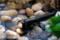 A black flashlight in a small stream Royalty Free Stock Photo