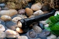 A black flashlight in a small stream