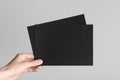 Black A5 Flyer / Invitation Mock-Up - Male hands holding black flyers on a gray background Royalty Free Stock Photo