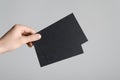 Black A6 Flyer / Postcard / Invitation Mock-Up - Male hands holding black flyers on a gray background Royalty Free Stock Photo