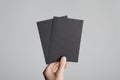 Black A6 Flyer / Postcard / Invitation Mock-Up - Male hands holding black flyers on a gray background Royalty Free Stock Photo