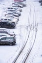 Black footprints of people and cars in a snow-covered parking lot.