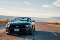 Black Ford Mustang GT convertible is parked by the infinite long road