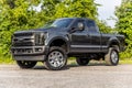 Black Ford pickup truck parked in a lush green grassy field.