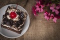 Black Forest Cake topping cherry putting on the white plate on the Sack Bags and wood table background there is the flower placed Royalty Free Stock Photo