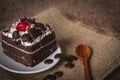 Black Forest Cake topping cherry putting on the white plate on the sack and wood background there are wood spoon and Chocolate Royalty Free Stock Photo