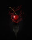 Black fork with a red cherry with drops and splashing water or drink Royalty Free Stock Photo