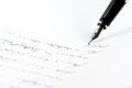 Black fountain pen is writing a letter or a manuscript on a white paper, copy space, close-up shot with selected focus Royalty Free Stock Photo