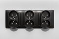 Black frame of a double grounded electrical socket in three rows on the gray wall of the room. Royalty Free Stock Photo