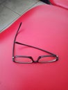 Black frame glasses lay on a red leather chair Royalty Free Stock Photo