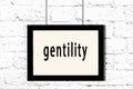 Black frame hanging on white brick wall with inscription gentility Royalty Free Stock Photo