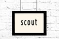 Black frame hanging on white brick wall with inscription scout Royalty Free Stock Photo