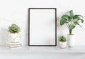 Black frame leaning on white shelve in bright interior with plants and decorations mockup 3D rendering