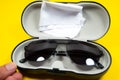Black frame mens sunglasses with glasses cleaning cloth and case on a yellow background