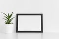 Black frame mockup with a aloe vera in a pot on a white table.Landscape orientation Royalty Free Stock Photo