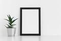 Black frame mockup with a aloe vera in a pot on a white table. Portrait orientation Royalty Free Stock Photo