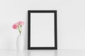 Black frame mockup with pink roses in a vase on a white table.Portrait orientation Royalty Free Stock Photo