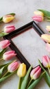 Black frame with vibrant yellow tulips on light neutral background Royalty Free Stock Photo